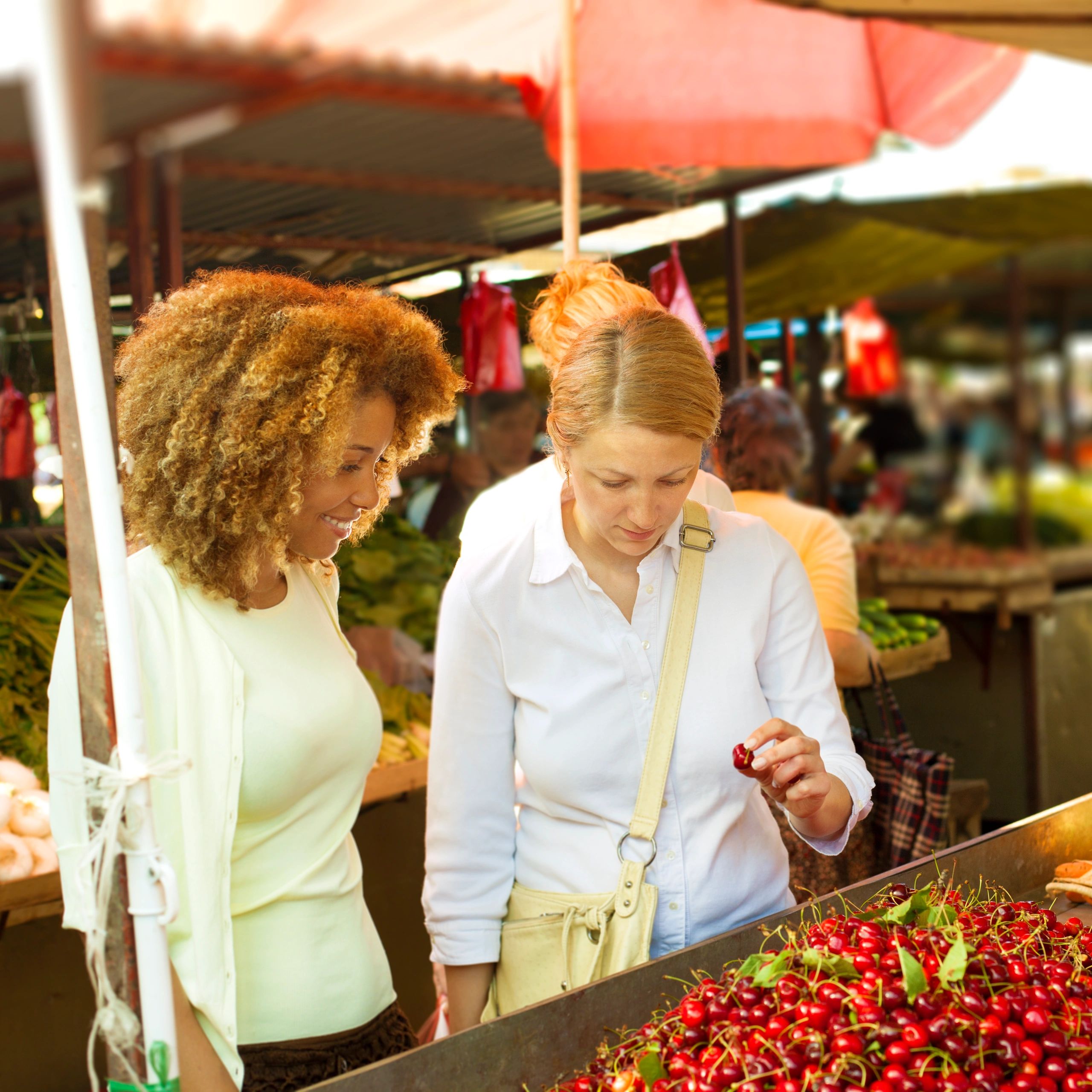 Shoppers at an open market selecting fresh produce